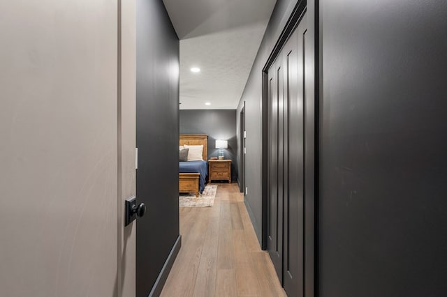 hallway featuring light wood-style floors, baseboards, and recessed lighting