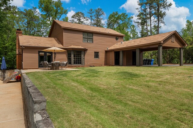 rear view of house with a chimney, a patio area, and a yard