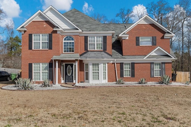 view of front of property with brick siding, a front lawn, and fence