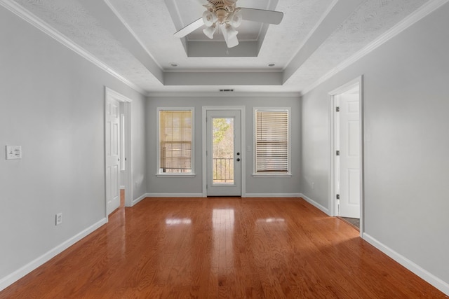 foyer with wood-type flooring, a tray ceiling, and crown molding