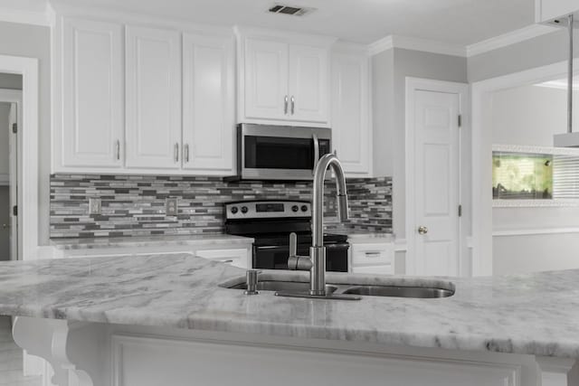 kitchen with light stone counters, stainless steel appliances, tasteful backsplash, crown molding, and white cabinets