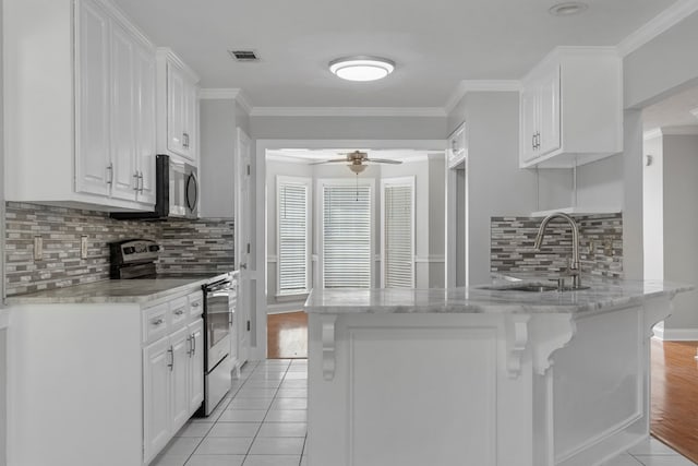 kitchen with stainless steel appliances, sink, white cabinetry, light tile patterned flooring, and kitchen peninsula