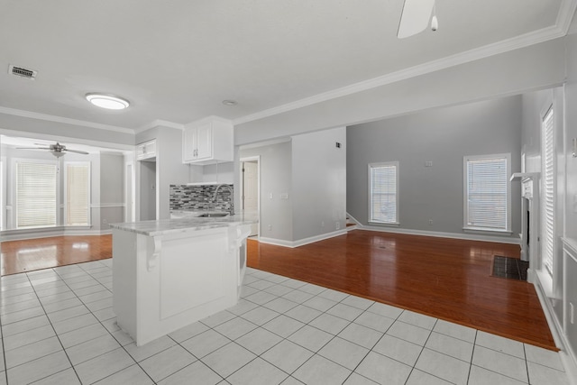 kitchen featuring crown molding, white cabinets, light tile patterned floors, and sink