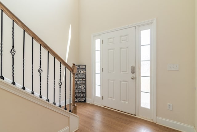 entrance foyer with wood finished floors, baseboards, and stairway