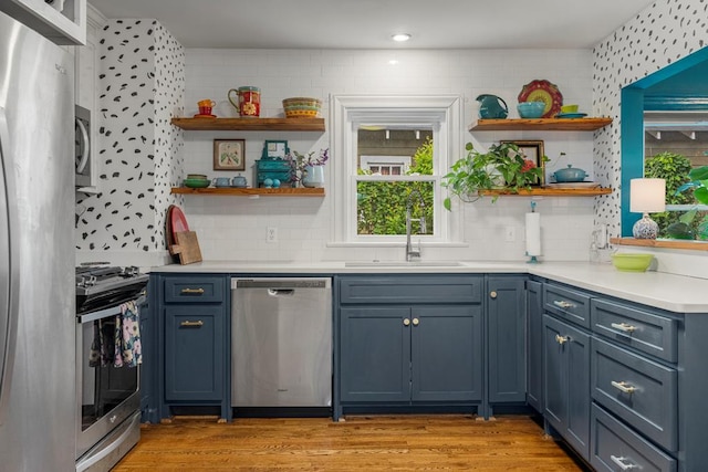 1445 22nd St, Columbus, GA 31901 - kitchen featuring stainless steel appliances, open shelves, light countertops, light wood-style flooring, and blue cabinetry