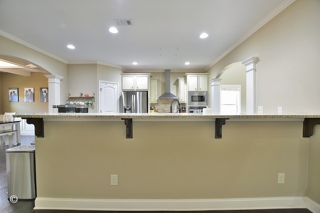 kitchen with a breakfast bar area, wall chimney exhaust hood, a spacious island, and appliances with stainless steel finishes