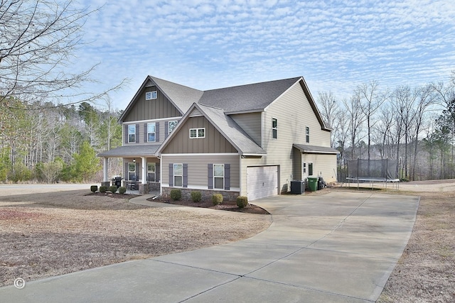 view of front of home featuring a garage, central AC unit, covered porch, and a trampoline