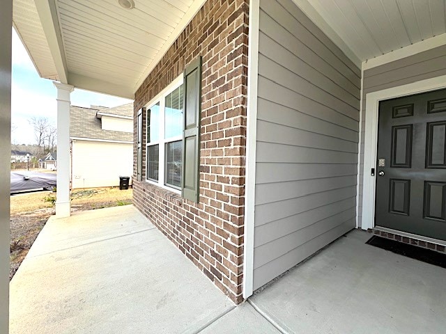 doorway to property with brick siding and a porch