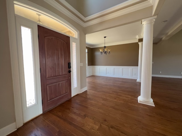 entrance foyer featuring a notable chandelier, dark hardwood / wood-style flooring, ornamental molding, and ornate columns