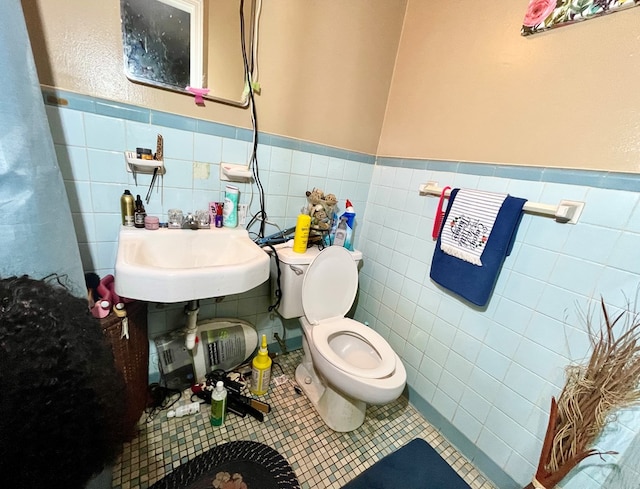 bathroom featuring tile patterned flooring, toilet, tile walls, and sink