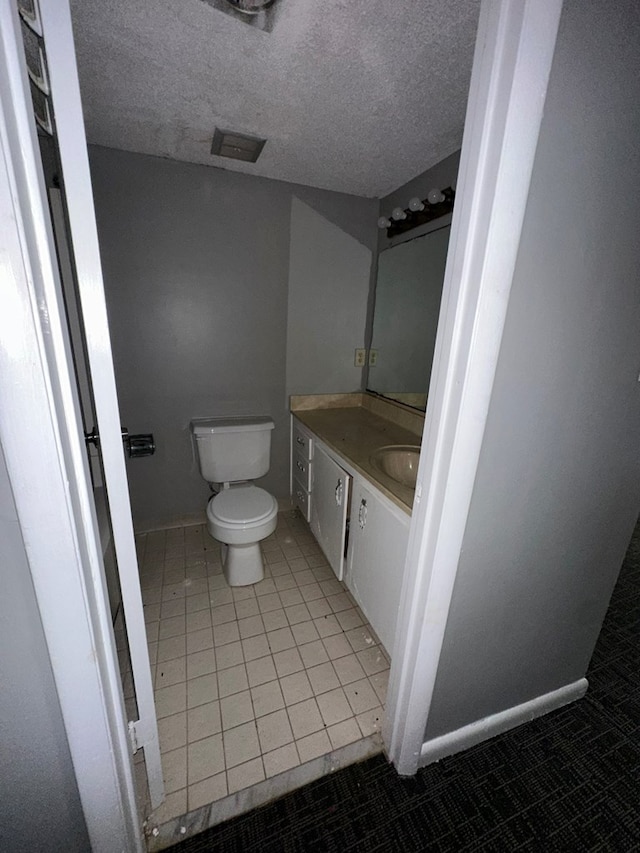 bathroom featuring toilet, a textured ceiling, vanity, and tile patterned floors