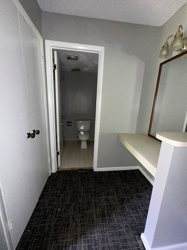 bathroom with tile patterned flooring, a textured ceiling, and toilet