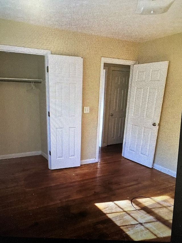 unfurnished bedroom with dark hardwood / wood-style floors and a closet