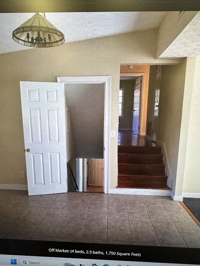 staircase featuring tile patterned flooring, a chandelier, and lofted ceiling