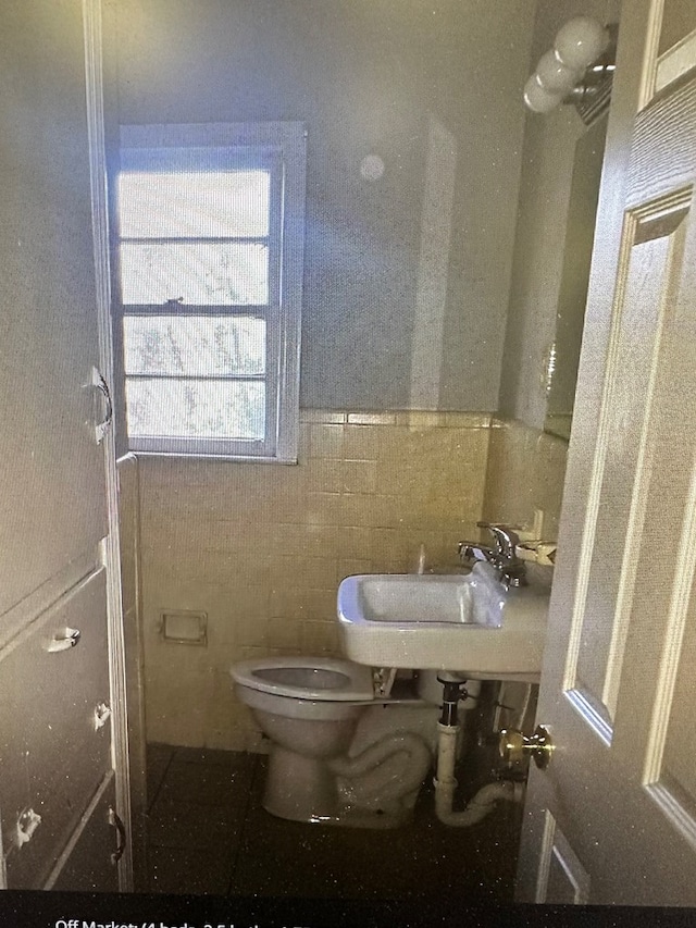 bathroom featuring sink, tile walls, and toilet