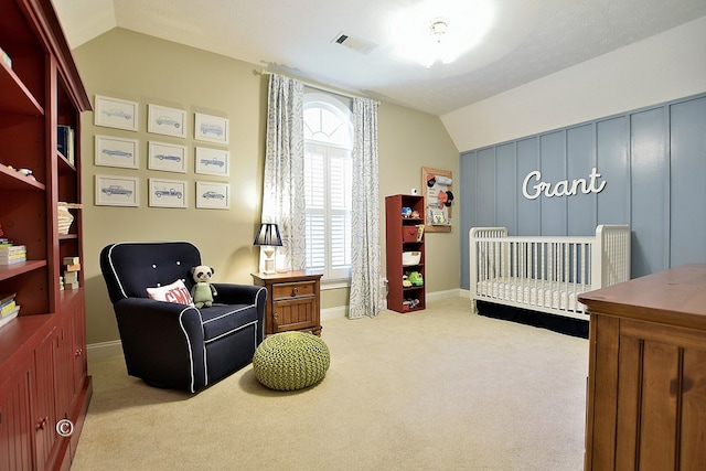 bedroom featuring light carpet, a nursery area, and lofted ceiling