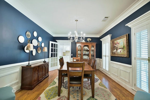 dining space with crown molding, plenty of natural light, an inviting chandelier, and hardwood / wood-style flooring