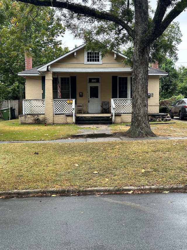 view of front of house featuring covered porch and a front lawn