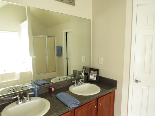 full bath featuring a sink, a tub to relax in, a shower stall, and double vanity