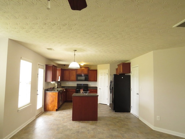 kitchen with dark countertops, visible vents, a center island, baseboards, and black appliances