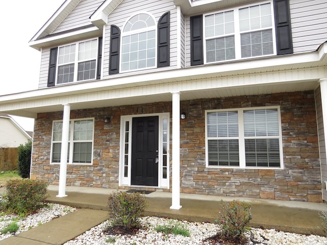 view of exterior entry with stone siding and covered porch