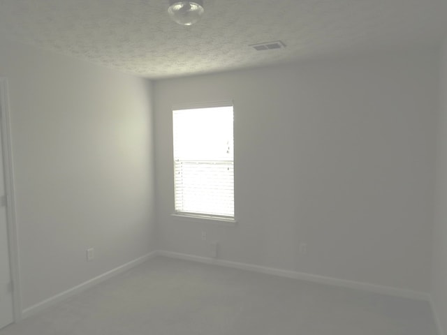 unfurnished room with visible vents, carpet flooring, a textured ceiling, and baseboards