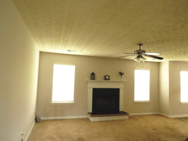 unfurnished living room with a wealth of natural light, visible vents, carpet floors, and a fireplace with raised hearth