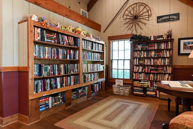 sitting room with bookshelves, wooden walls, and wood finished floors