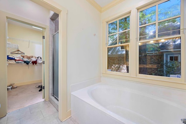 full bath featuring a walk in closet, a shower stall, a garden tub, and baseboards