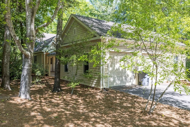 exterior space featuring a garage, driveway, and a shingled roof
