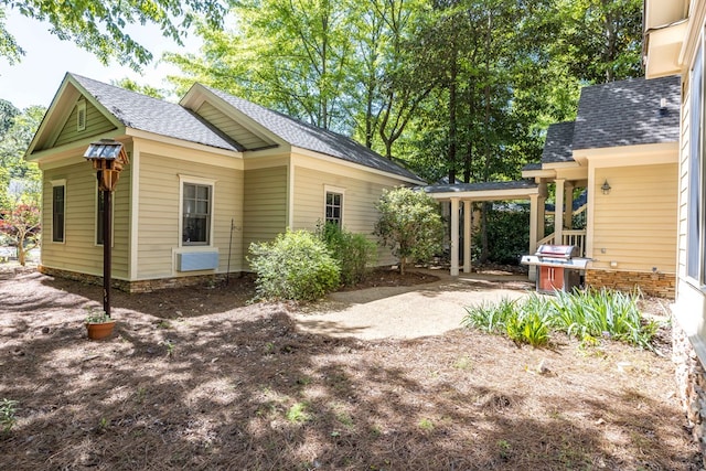 view of side of home featuring a patio area and a shingled roof