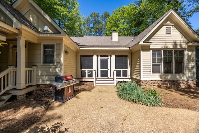 back of property featuring a chimney, stone siding, and a shingled roof