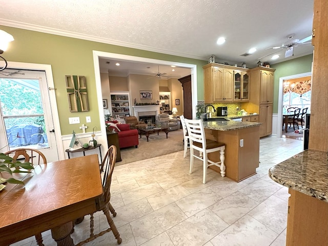 4804 Champions Way, Columbus, GA 31909 - kitchen with a ceiling fan, a kitchen breakfast bar, crown molding, a peninsula, and glass insert cabinets