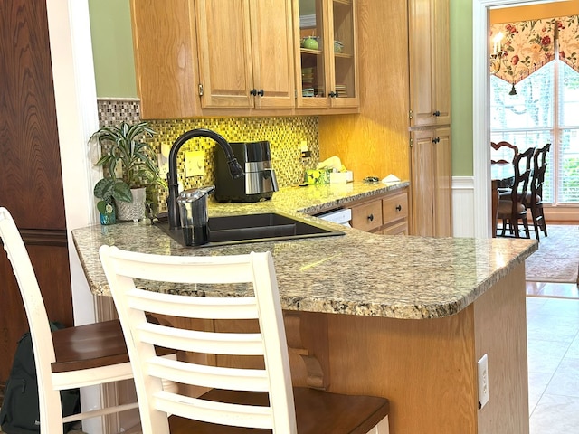 4804 Champions Way, Columbus, GA 31909 - kitchen with backsplash, a breakfast bar area, glass insert cabinets, light stone countertops, and tile patterned floors