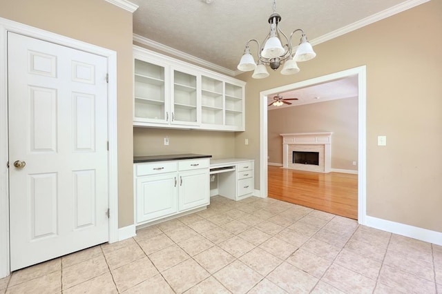 4589 Carnoustie Ln, Columbus, GA 31909 - kitchen featuring crown molding, a chandelier, a fireplace, light tile patterned flooring, and glass insert cabinets