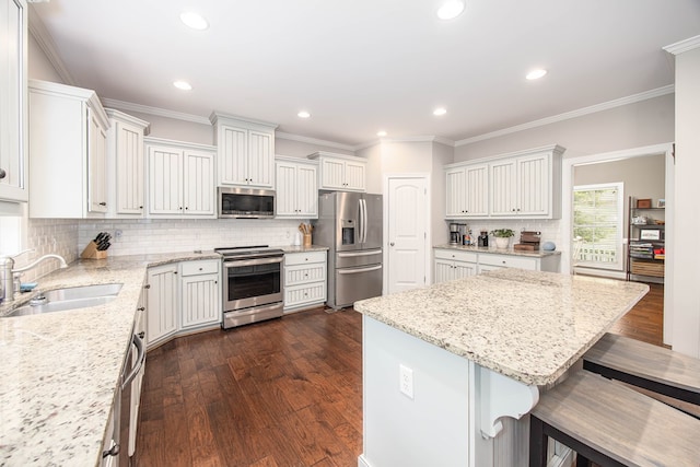 6027 Wellesley Dr, Columbus, GA 31904 - kitchen featuring appliances with stainless steel finishes, a sink, a kitchen bar, decorative backsplash, and light stone countertops