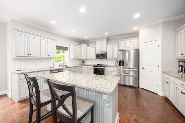 6027 Wellesley Dr, Columbus, GA 31904 - kitchen featuring appliances with stainless steel finishes, a breakfast bar, a kitchen island, decorative backsplash, and crown molding
