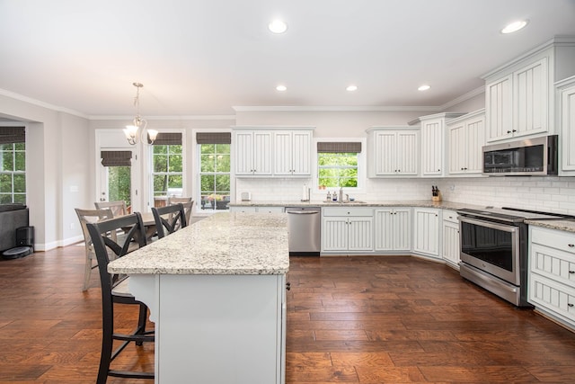 6027 Wellesley Dr, Columbus, GA 31904 - kitchen with appliances with stainless steel finishes, a kitchen breakfast bar, tasteful backsplash, a chandelier, and ornamental molding