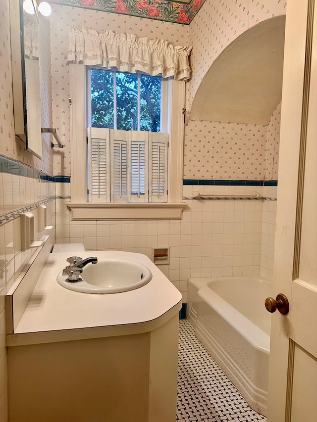 bathroom with tile walls, tile patterned floors, vanity, and a bathing tub