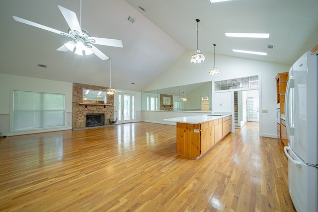 5604 Holland Dr, Columbus, GA 31909 - kitchen featuring freestanding refrigerator, a skylight, ceiling fan, high vaulted ceiling, and a stone fireplace
