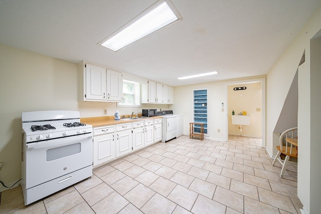 5604 Holland Dr, Columbus, GA 31909 - kitchen featuring gas range gas stove, a sink, white cabinets, light countertops, and washer / clothes dryer