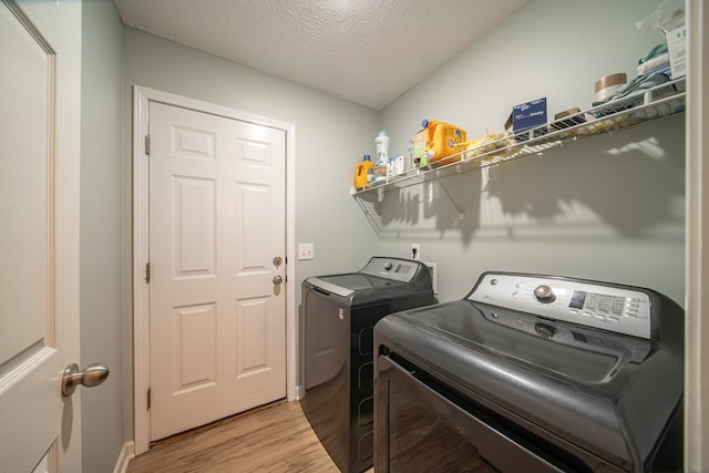 washroom with washer and clothes dryer, light hardwood / wood-style floors, and a textured ceiling