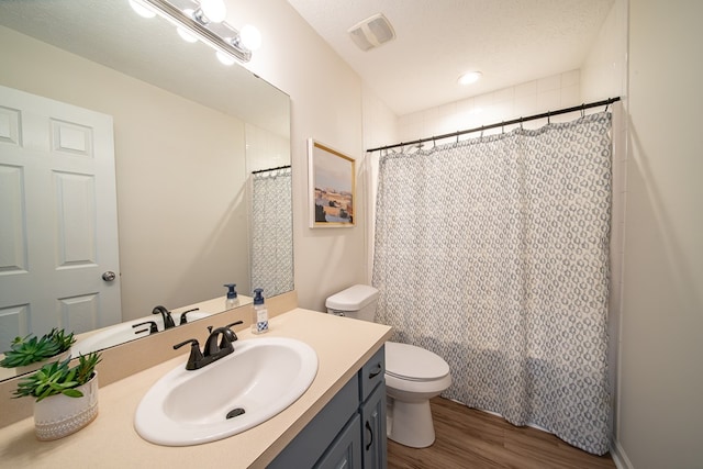 bathroom featuring hardwood / wood-style flooring, vanity, a textured ceiling, curtained shower, and toilet