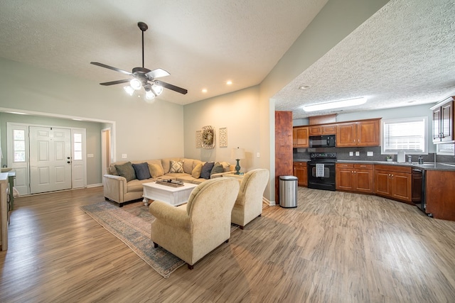 living room featuring ceiling fan, hardwood / wood-style floors, and a textured ceiling