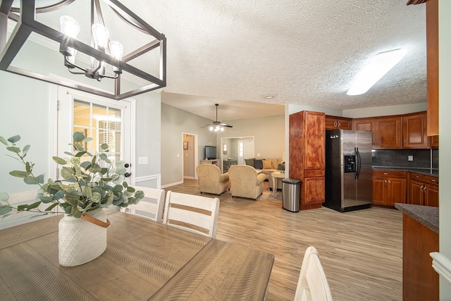 dining space with ceiling fan with notable chandelier, a textured ceiling, and light wood-type flooring