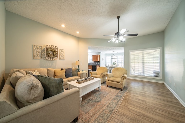 living room featuring wood-type flooring, lofted ceiling, ceiling fan, and a textured ceiling