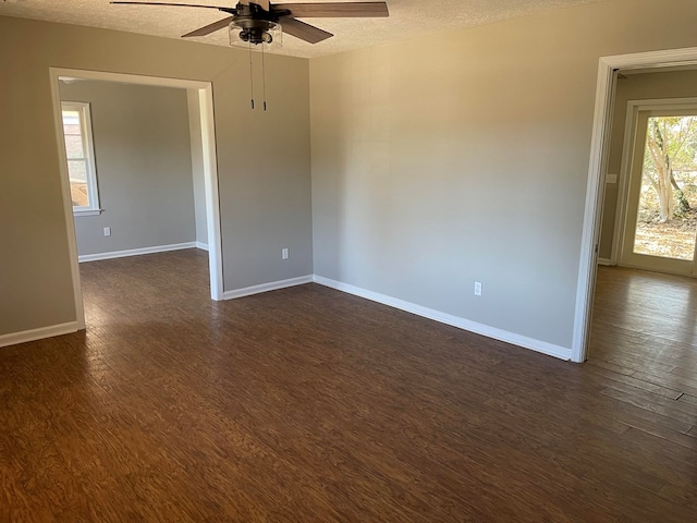 spare room with dark wood-style floors, ceiling fan, baseboards, and a textured ceiling