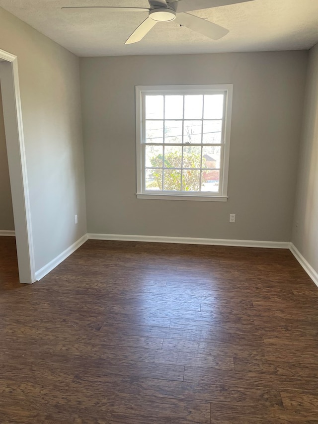spare room with dark wood finished floors, ceiling fan, and baseboards