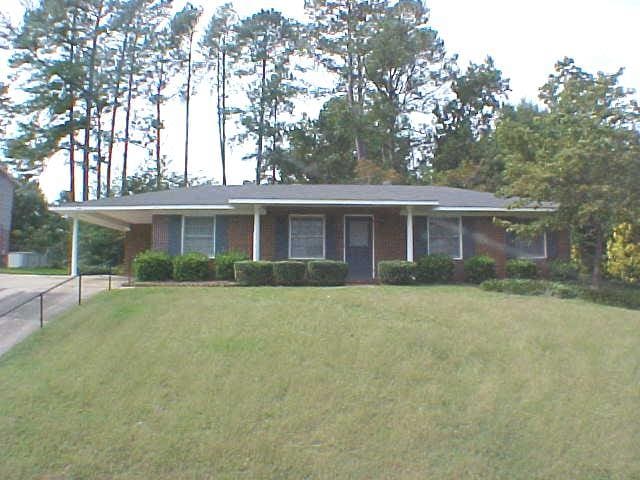 single story home featuring concrete driveway, a front lawn, and an attached carport