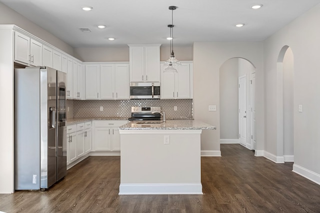 kitchen featuring light stone countertops, hanging light fixtures, stainless steel appliances, a center island with sink, and white cabinets